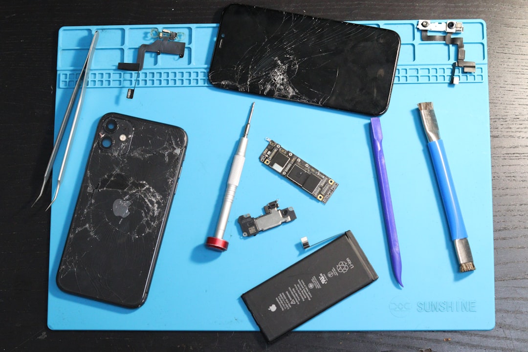 A disassembled iPhone and repair tools on a mat.
