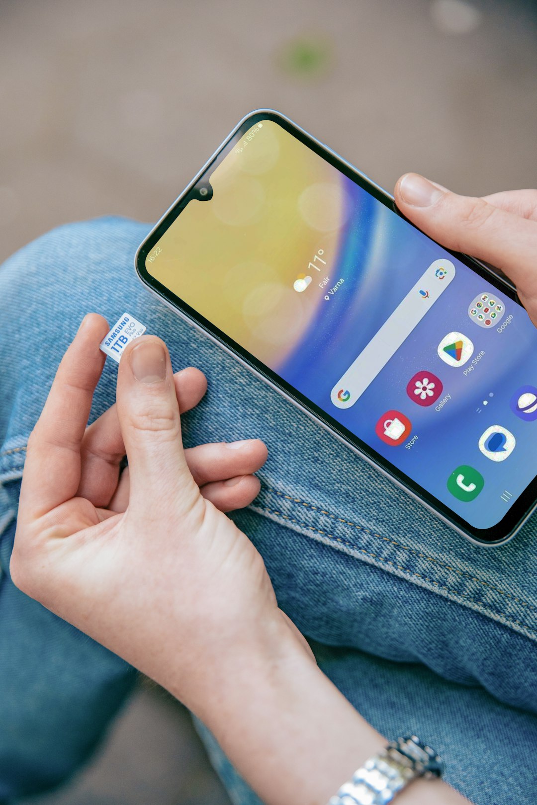 A person sitting on the ground holding a cell phone
