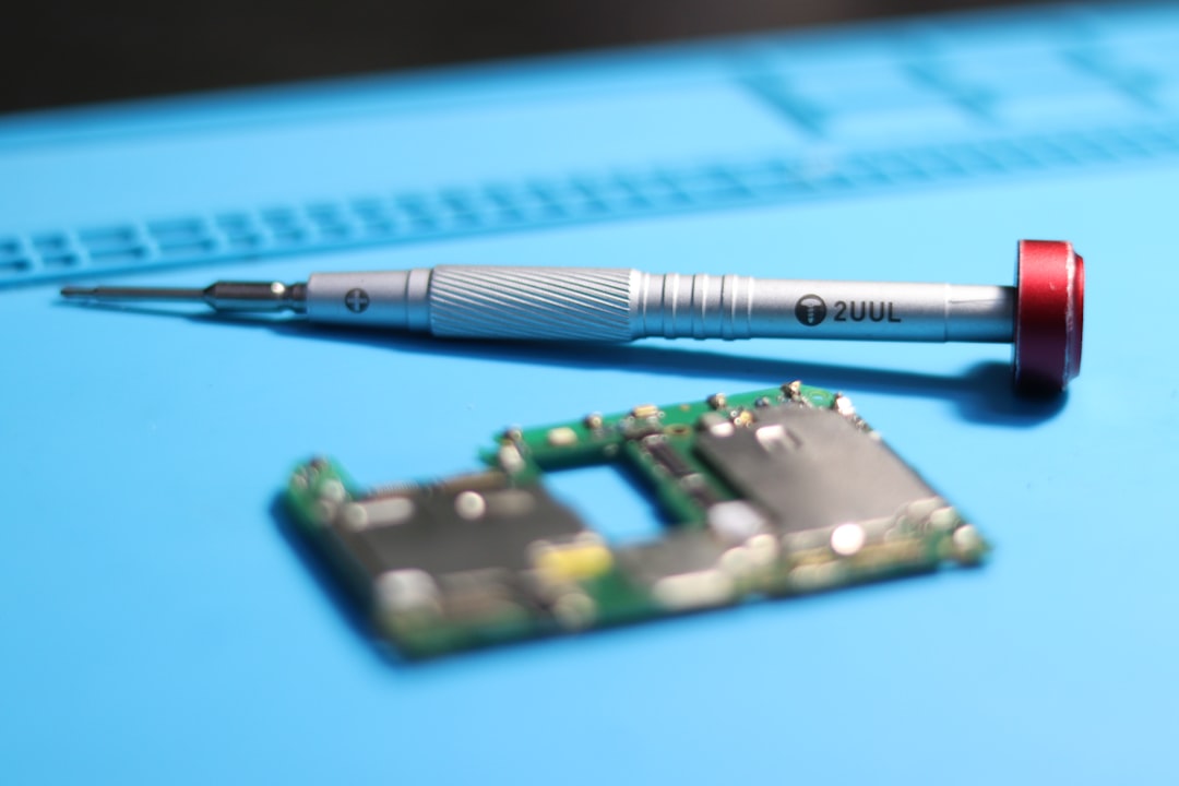 A screwdriver and circuit board on a work mat.