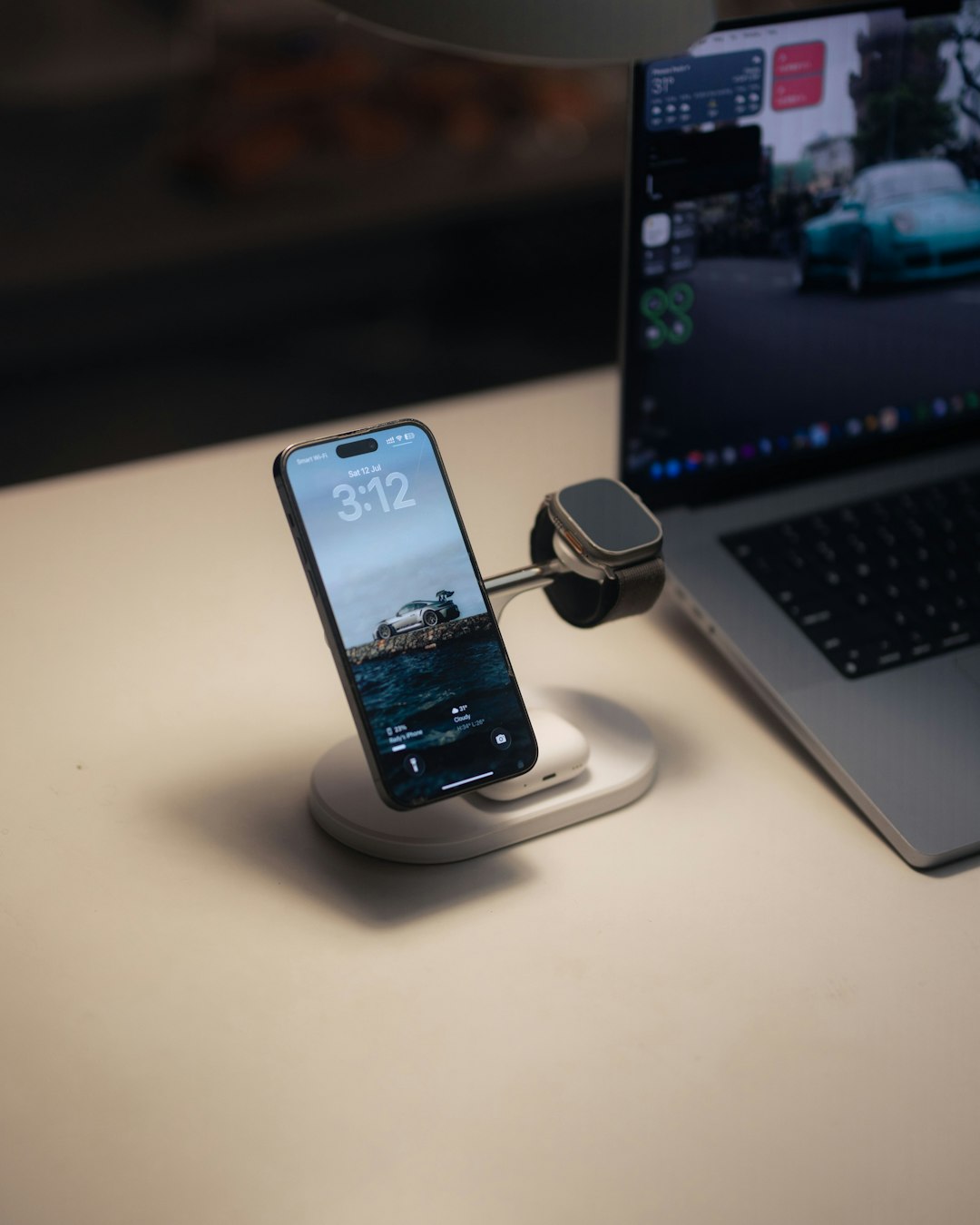 Smartphone and smartwatch charging on desk with laptop