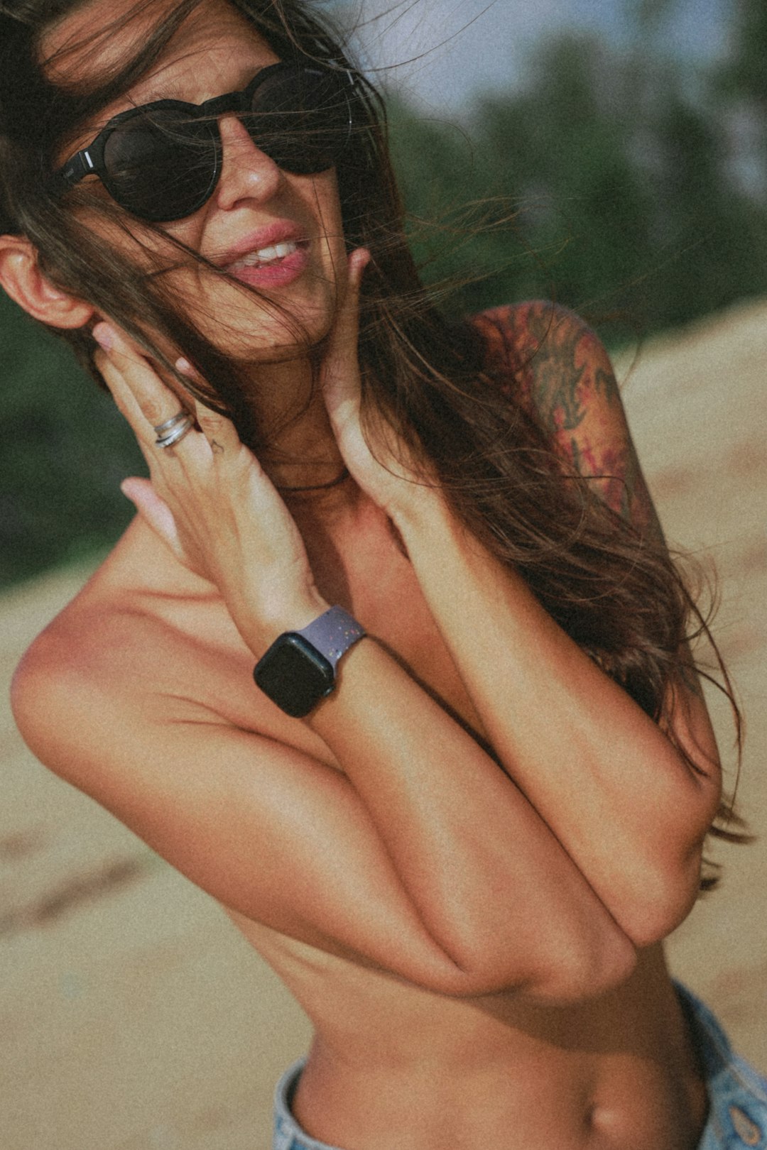 Woman poses with sunglasses and a watch.