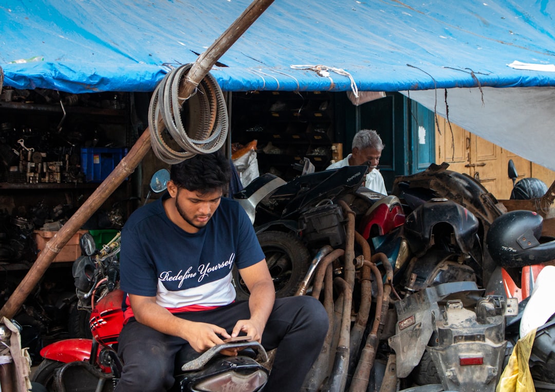 Man sitting in a cluttered workshop with motorcycles and parts