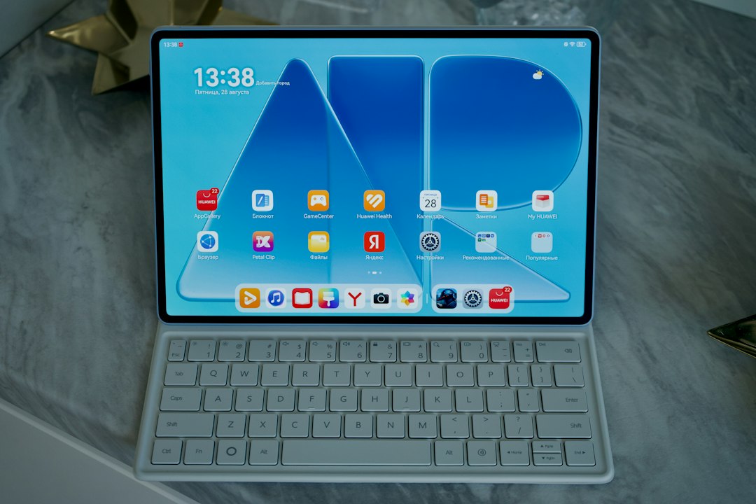 A tablet with a blue home screen and a white keyboard on a marble surface