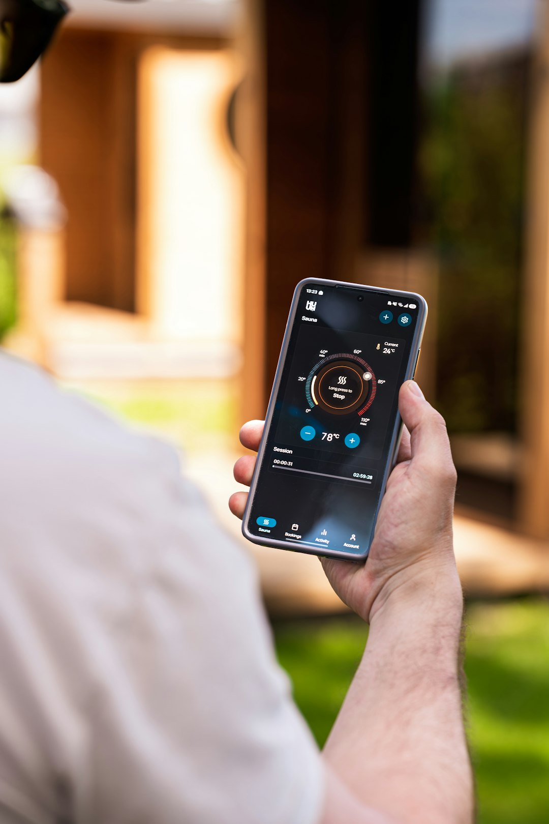 Hand holding smartphone with smart home interface outdoors